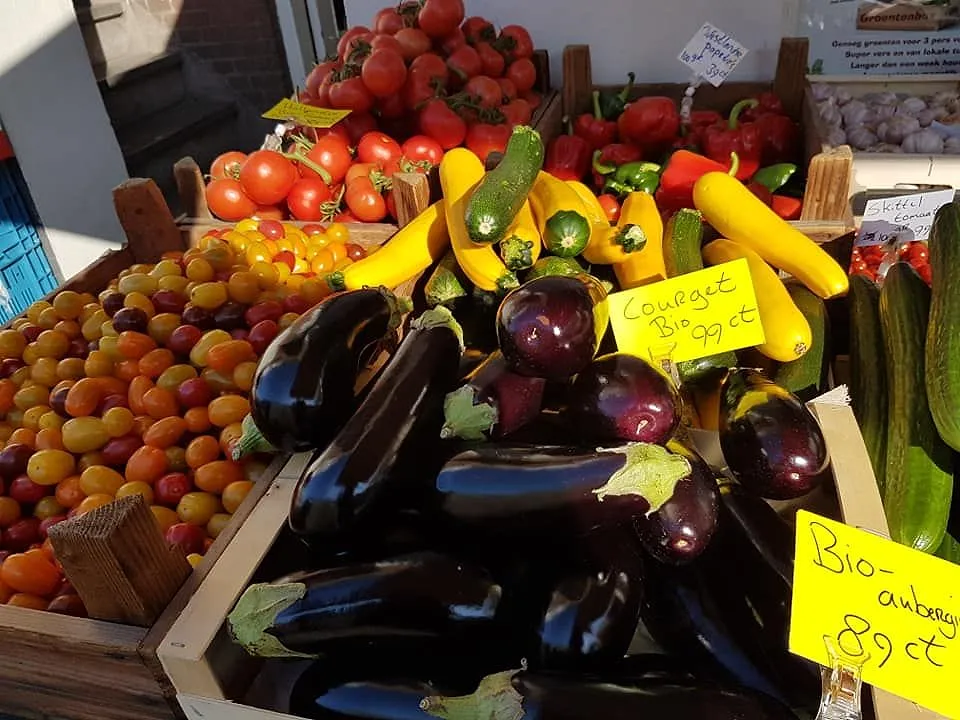 Kratten met aubergines, courgettes en tomaten met handgeschreven prijskaartjes.