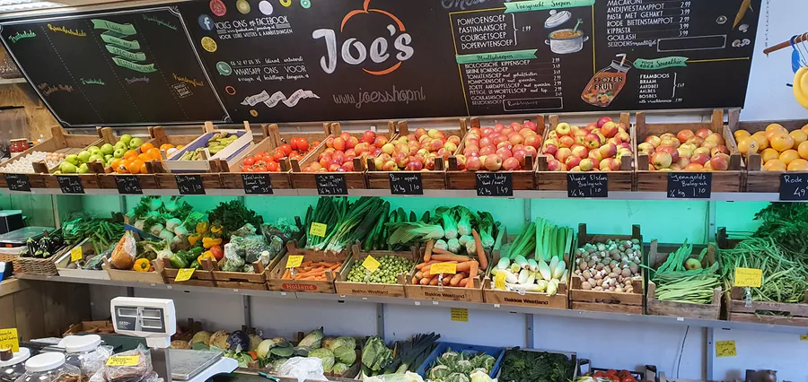 De winkel van binnen: kratten groente en fruit onder de krijtborden met het Joe's logo.